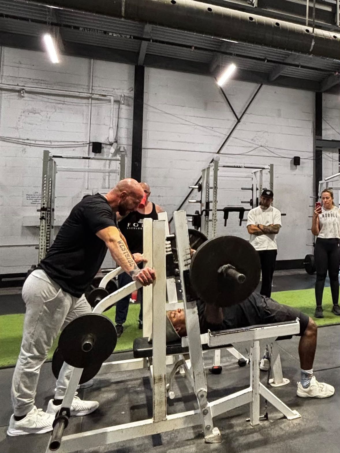 Craig Bongelli coaching a bench press on the platform at a seminar